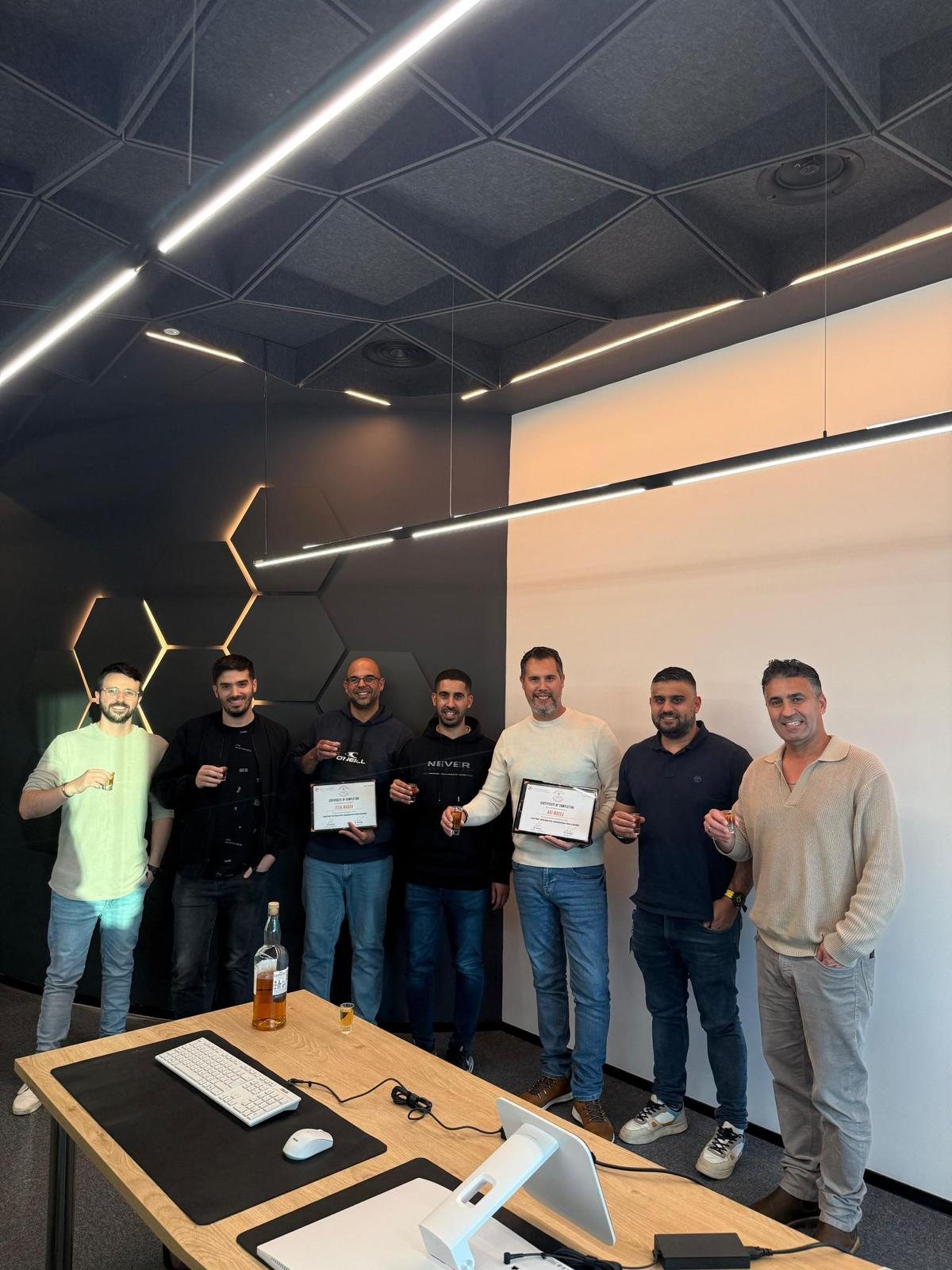 Course graduates holding their certificates of completion at the academy